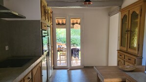 Eine Küche mit Holzausstattung, einer Arbeitsplatte und einer Tür zu einem Außenbereich mit Tisch und Stühlen.