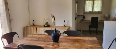 Un coin repas avec une table en bois, des chaises noires et un vase contenant des plantes séchées.