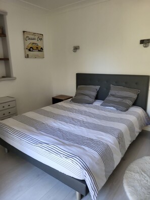 A bedroom with a bed, a nightstand, a wall-mounted light, and a shelf with a vintage car poster. - Maison provençale 7 persons swimming pool absolute calm ideal family (Saint-Cézaire-sur-Siagne)