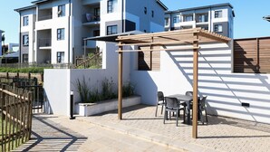 Un moderno edificio de apartamentos con un área de estar al aire libre cubierta y una valla de madera.