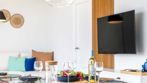 Un comedor moderno con una mesa dispuesta para dos, una botella de vino y un televisor montado en la pared.
