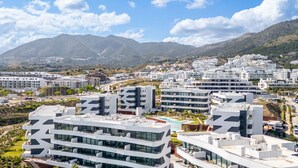 Una zona residencial moderna con edificios de varios pisos, cielo despejado y montañas al fondo.
