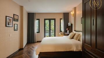 Une chambre d’hôtel avec un grand lit, un plancher en bois, une vue à travers une porte vitrée et une armoire.