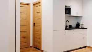 Appartement (1 A) | Privékeuken | Een koelkast, een kookplaat, een waterkoker, kookgerei, borden en bestek