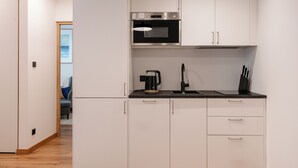 Une cuisine moderne avec des meubles blancs, un plan de travail noir, une machine à café et un four à micro-ondes.