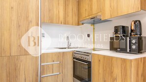A compact kitchen with wooden cabinetry, a built-in oven, and a microwave on the countertop. - 336 -Bloomfields Stylish 1BR In Al Maryah Vista (Abu Dabi)