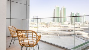 Ein Balkon mit zwei Korbstühlen, einer Glastrennwand und Blick auf die Stadt.