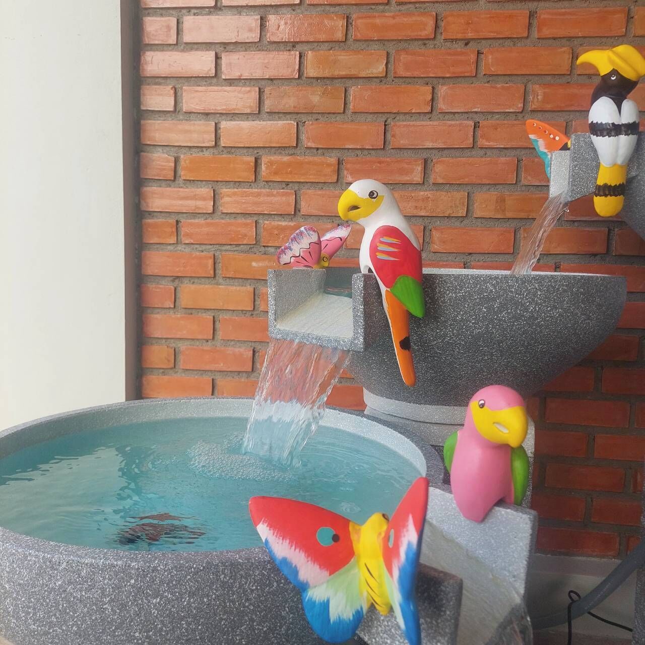 A bird bath with colorful bird figurines and a butterfly decoration.