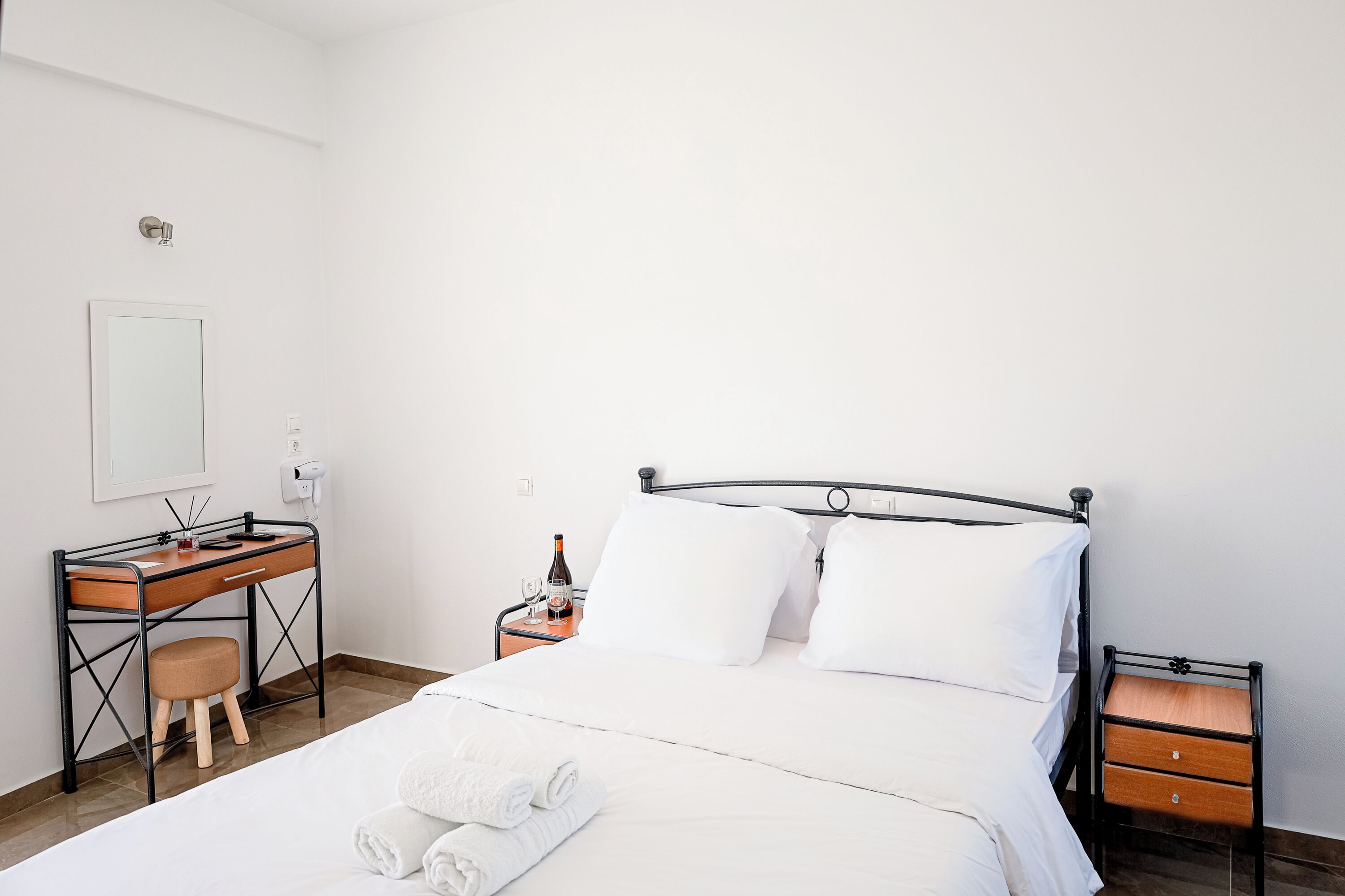 Une chambre d’hôtel bien rangée, avec un lit, un bureau et une chaise.