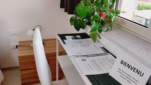 A neatly arranged workspace with a desk, chair, and a potted plant. Papers and a welcome card are on the desk. - UN PASSO DAL PORTO (Palermo)