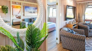 A cozy living room with a large mirror, a sofa, a TV, and a dining area with a table and chairs. - Luxury Family Chalet | BBQ Deck & Lagoon View (Knysna)