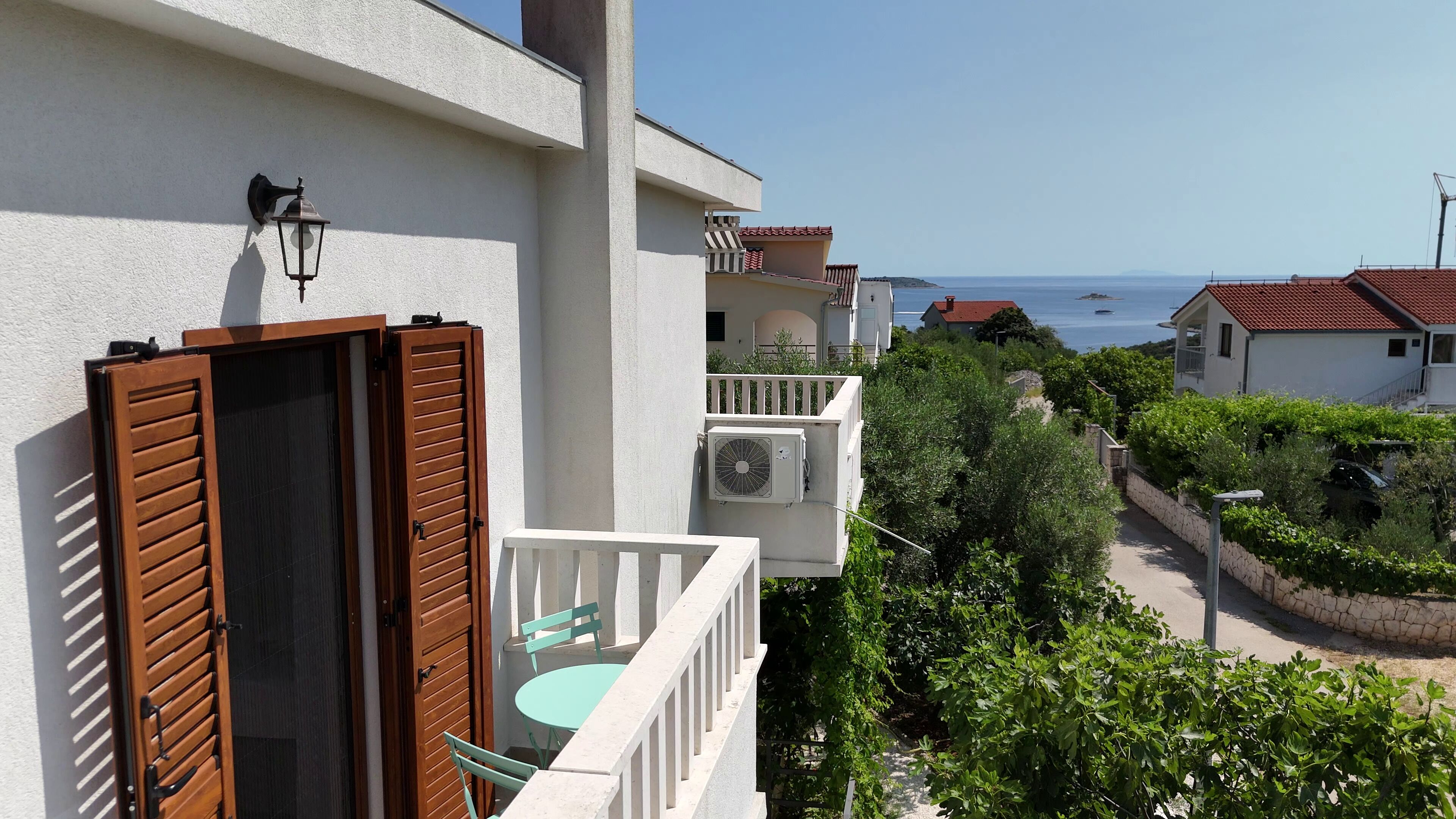 A balcony with wooden shutters, a small table, and a chair.