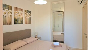 A bedroom with a bed, a nightstand, a lamp, and a mirror. - Sea View Holiday Apartment 073 (Durres)