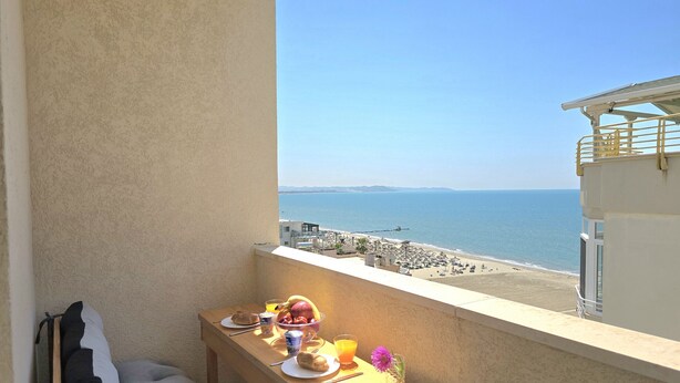 A balcony with a table set for breakfast, overlooking a beach and the sea. - Sea View Holiday Apartment 073 (Durres)