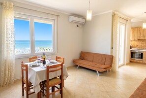 A dining area with a table set for two, a sofa, and a view of the sea. - Happy Stay Apartment 088 (Durres)