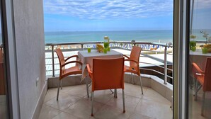 Ein Balkon mit Tisch und Stühlen mit Blick auf einen Strand und einen klaren Himmel.