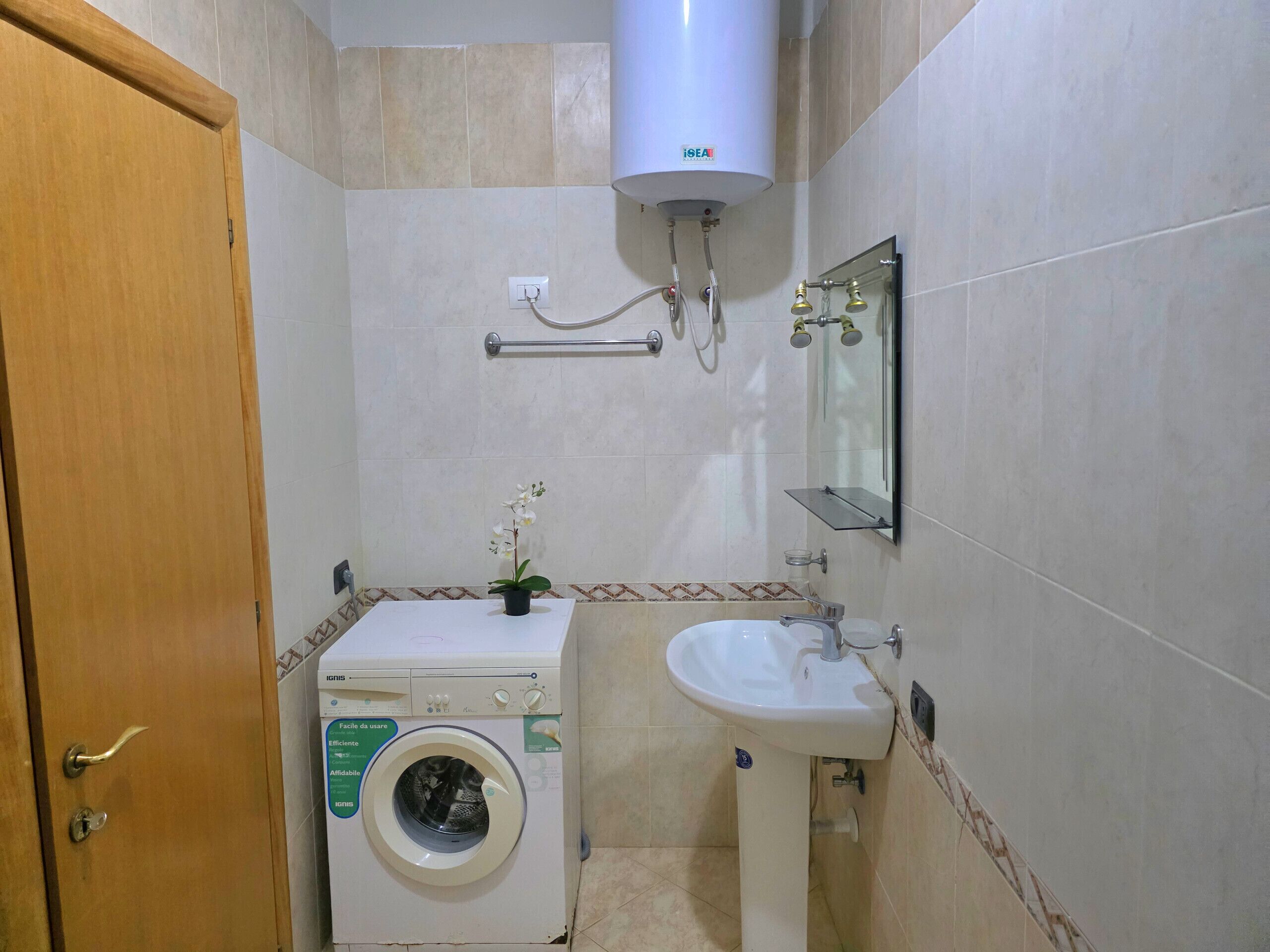 Une petite salle de bain équipée d’un lave-linge, d’un lavabo et d’un porte-serviettes.