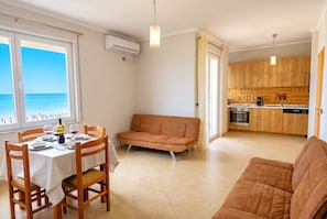 Un comedor con una mesa dispuesta para cuatro personas, un sofá y una cocina al fondo.