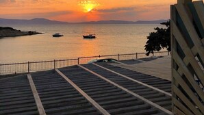 A sunset view from a covered walkway with steps leading down to a waterfront. - Deniz Evi (Cesme)