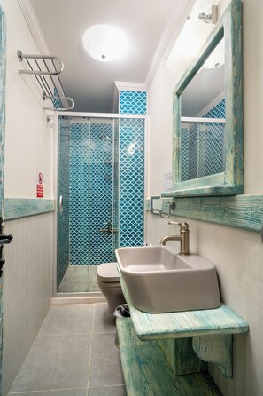 Un baño con ducha, inodoro, lavabo y espejo.