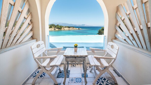 A balcony with two white chairs and a small table, overlooking a turquoise sea and distant mountains. - Deniz Evi (Cesme)
