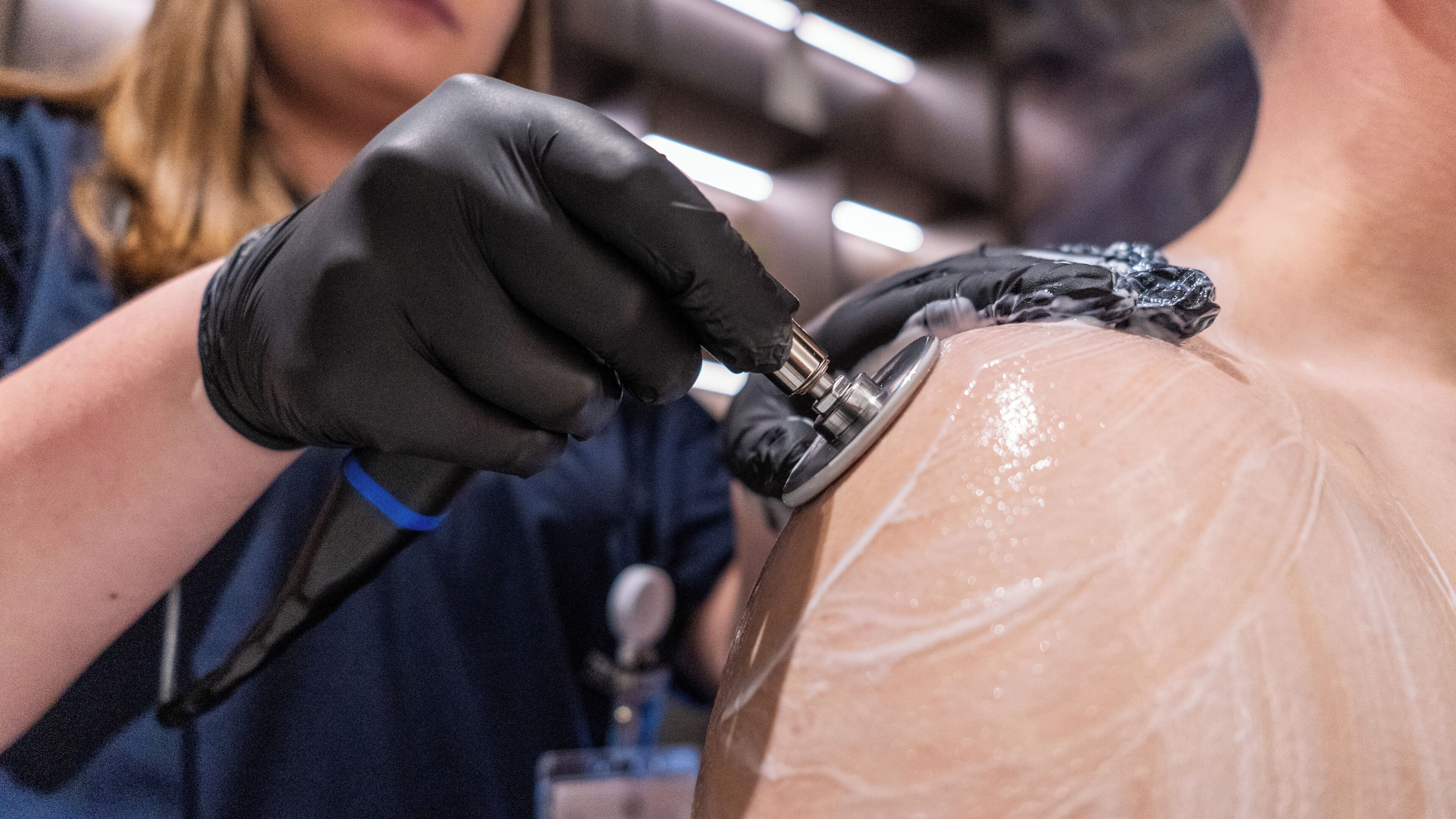 A person using a medical device on another person's skin.