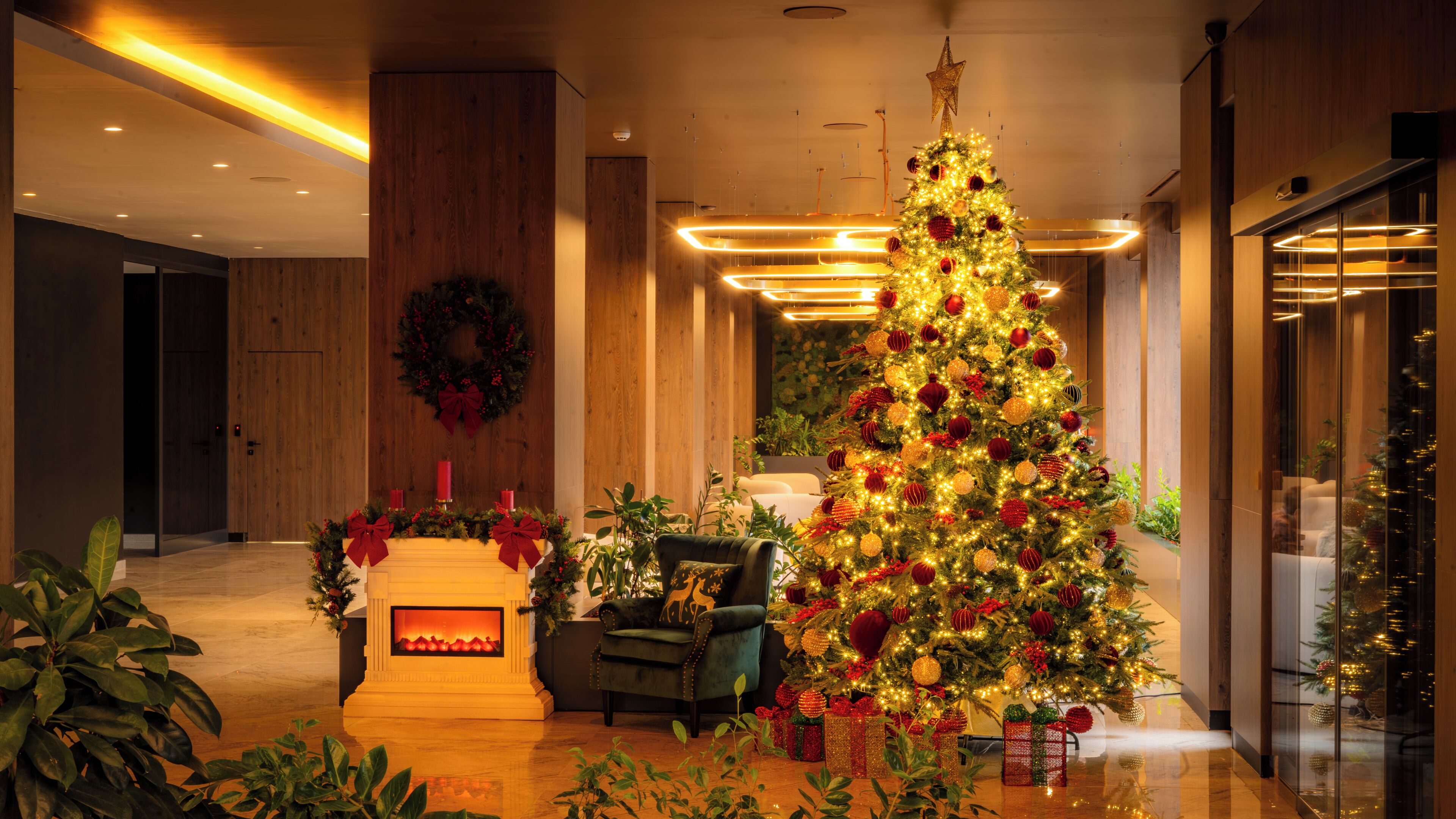 A modern hotel lobby with a large Christmas tree, a fireplace, and a seating area.