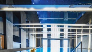Une chambre d’hôtel avec un lit, un verre contenant une boisson et une vue sur une piscine intérieure.