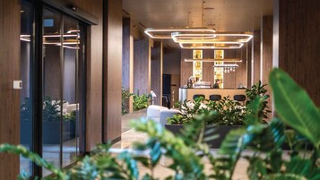 Un interior moderno con una zona de bar, asientos y plantas.
