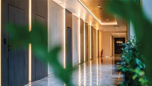 Un couloir d’hôtel moderne, avec un long couloir, des portes et un comptoir d’accueil situé au fond.