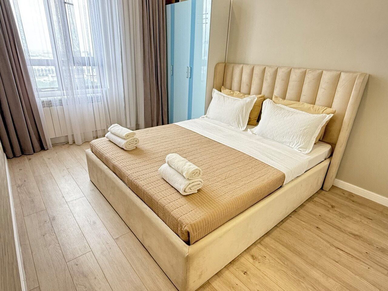Une chambre d’hôtel avec un grand lit, un plancher en bois et une vue par la fenêtre, qui est dotée de rideaux.
