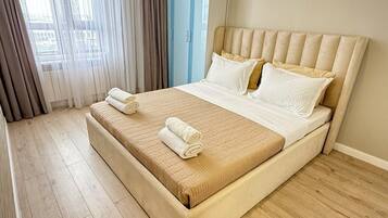 Une chambre d’hôtel avec un grand lit, un plancher en bois et une vue par la fenêtre, qui est dotée de rideaux.