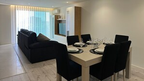 Un espace repas moderne avec une table rectangulaire dressée pour six personnes, entourée de chaises noires.