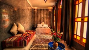 A cozy bedroom with a bed, a sofa, a decorative vase, and a window with warm lighting. - Le Matin, Riad 111 and Spa (Marrakech)