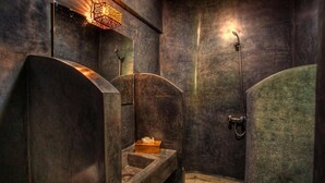 A modern bathroom with a curved vanity, a shower with a handheld showerhead, and a wall-mounted light fixture. - Le Matin, Riad 111 and Spa (Marrakech)