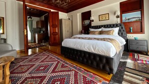 A spacious bedroom with a large bed, wooden ceiling, and a chandelier.