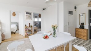 Un espace de restauration moderne et bien éclairé, avec une table blanche, des chaises et un vase de fleurs.