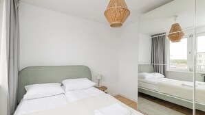 Une chambre à coucher moderne avec un grand lit, une table de chevet, un miroir et un luminaire suspendu.