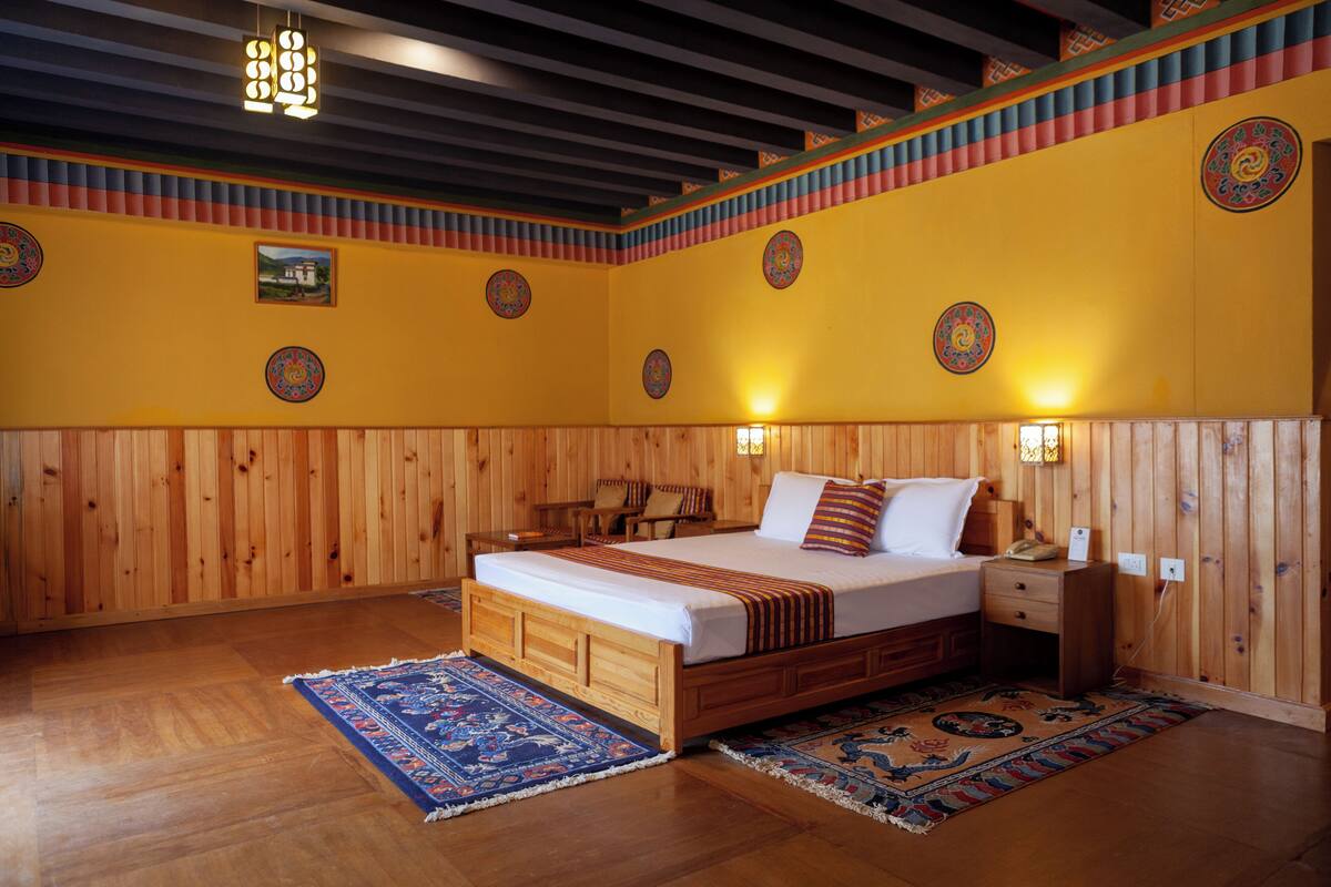 Habitación con paneles de madera, una cama, una mesita de noche y luces fijadas a la pared.