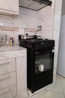 A kitchen with a black stove, white marble tiles, and a white countertop.