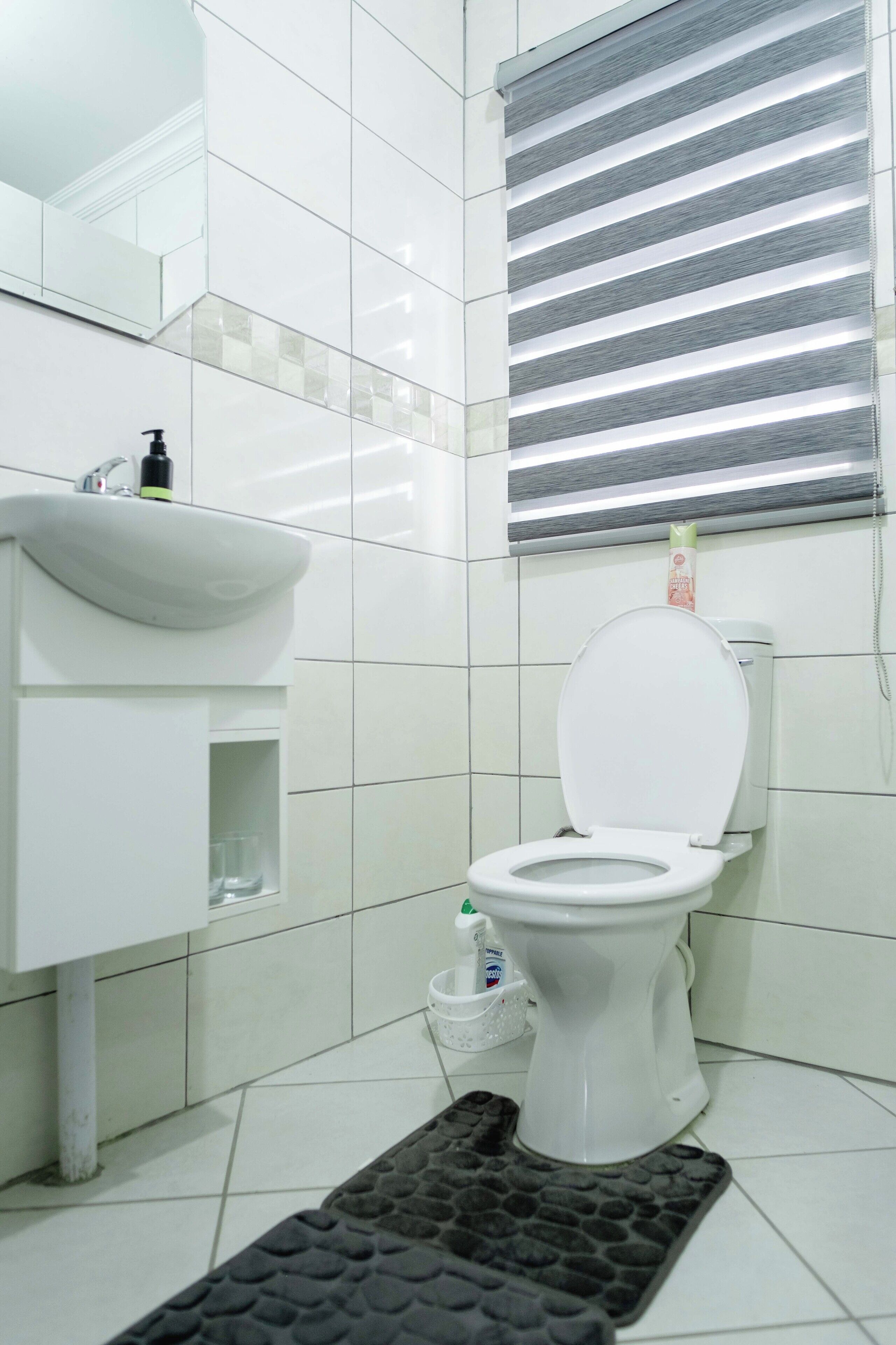 A modern bathroom with a white toilet, a sink, and a mirror.