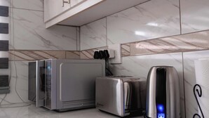Een moderne keuken met witte kasten, een magnetron, een broodrooster en een koffiezetapparaat op het aanrecht.