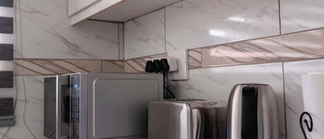 Una cocina moderna con armarios blancos, un microondas, un tostador y una cafetera sobre la encimera.