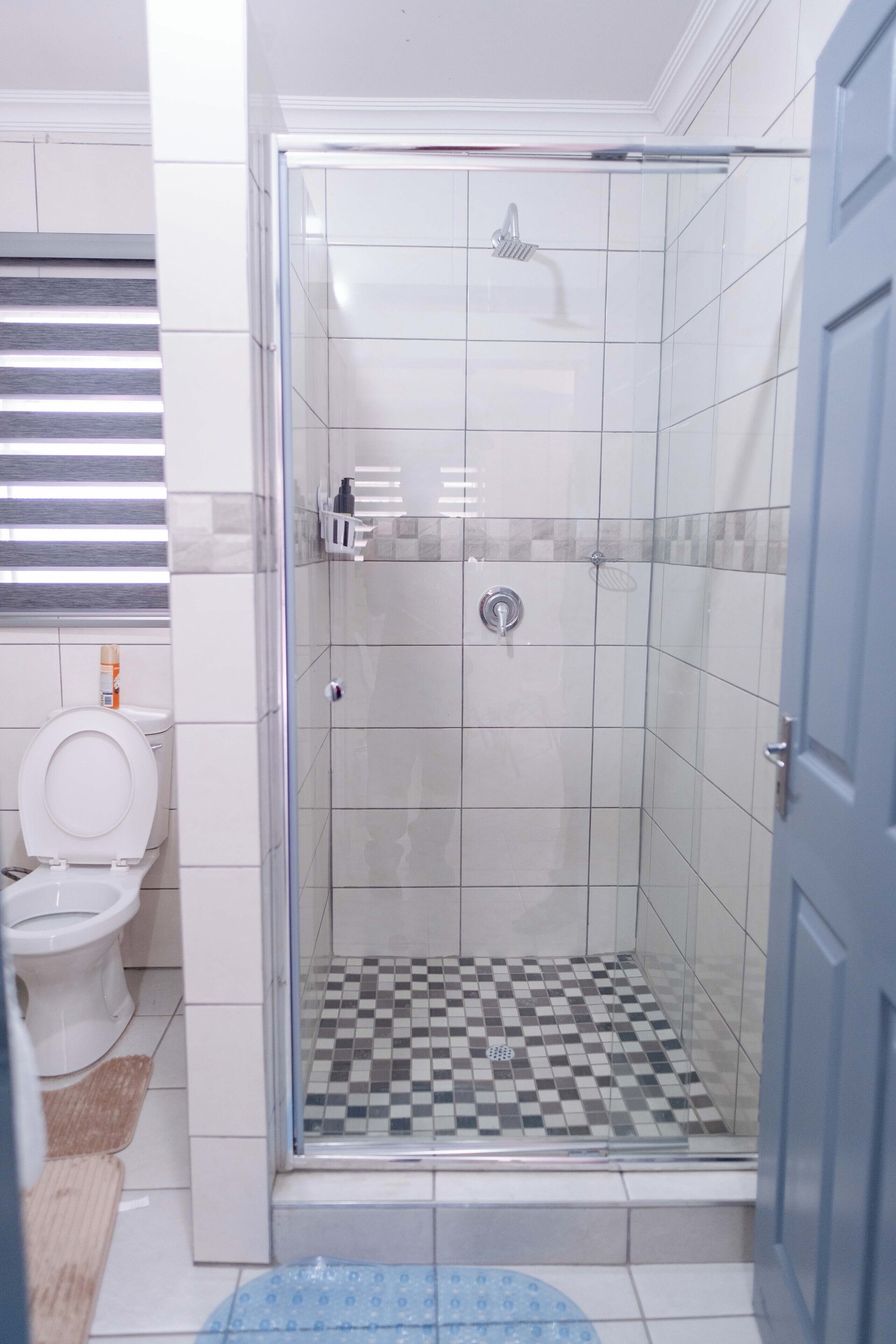 A bathroom with a glass-enclosed shower, a toilet, and a sink.