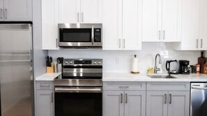 A modern kitchen with stainless steel appliances, white cabinets, and a wooden floor. - ReeseStreetUnit2inPhilly. (Philadelphia)