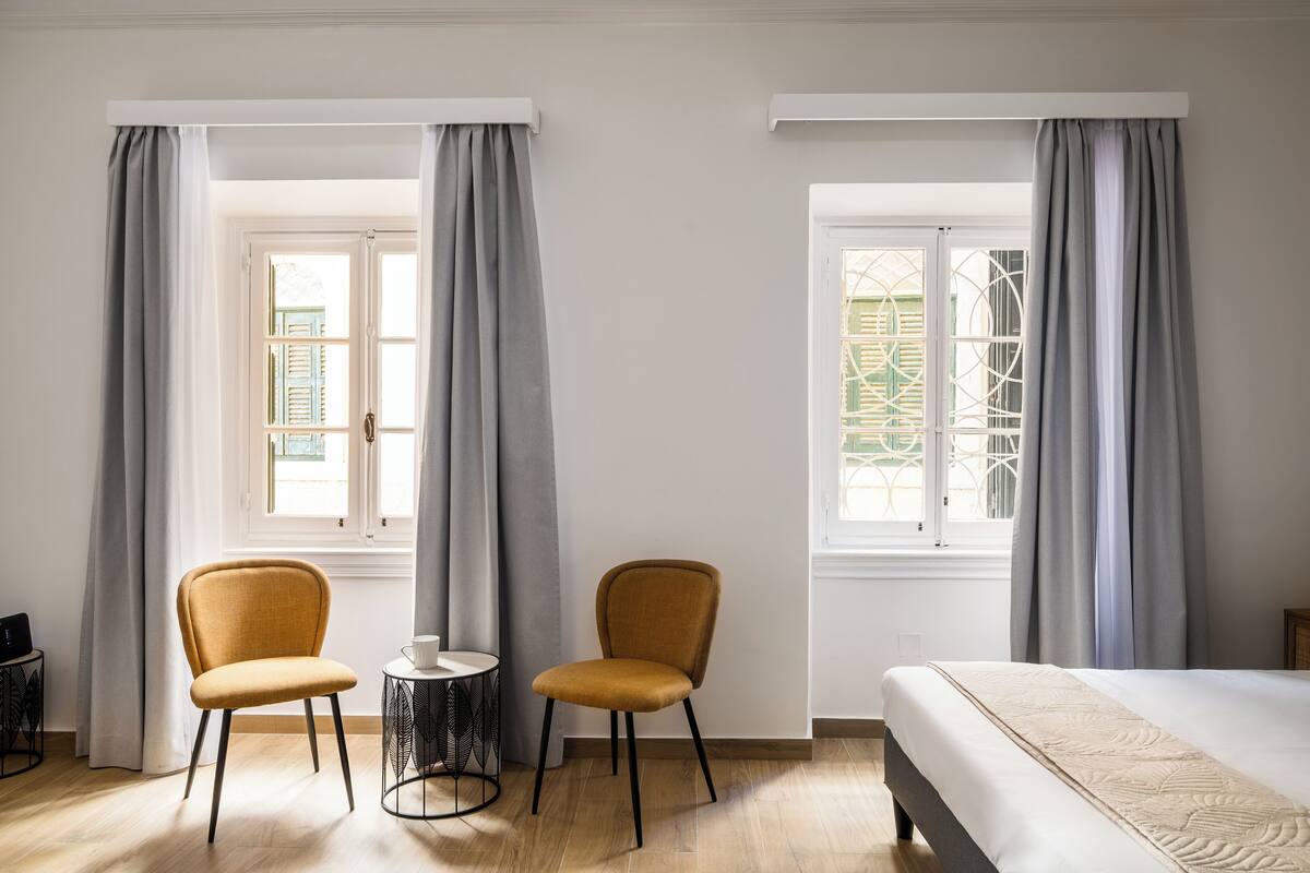 Ein Zimmer mit zwei Stühlen, einem kleinen Tisch und einem Bett.