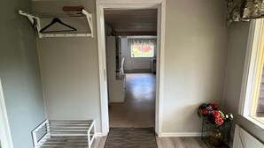 Een hal met een houten vloer, een hanglamp en een deur naar een andere kamer.