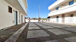 A building with a tiled courtyard, multiple windows, and a clear sky. - Casa Vacanze Marello - A 400 M Dalla Spiaggia (Salve)