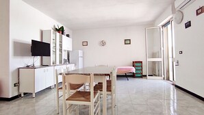 A compact kitchen with white cabinets, a dining table with chairs, a television, and a small plant. - Casa Vacanze Marello - A 400 M Dalla Spiaggia (Salve)
