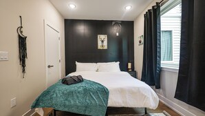 A bedroom with a bed, a wall-mounted artwork, a bedside table, and a window with curtains. - 1Bed/1Bath_KingBed Central+W/D+WIFi (Philadelphia)